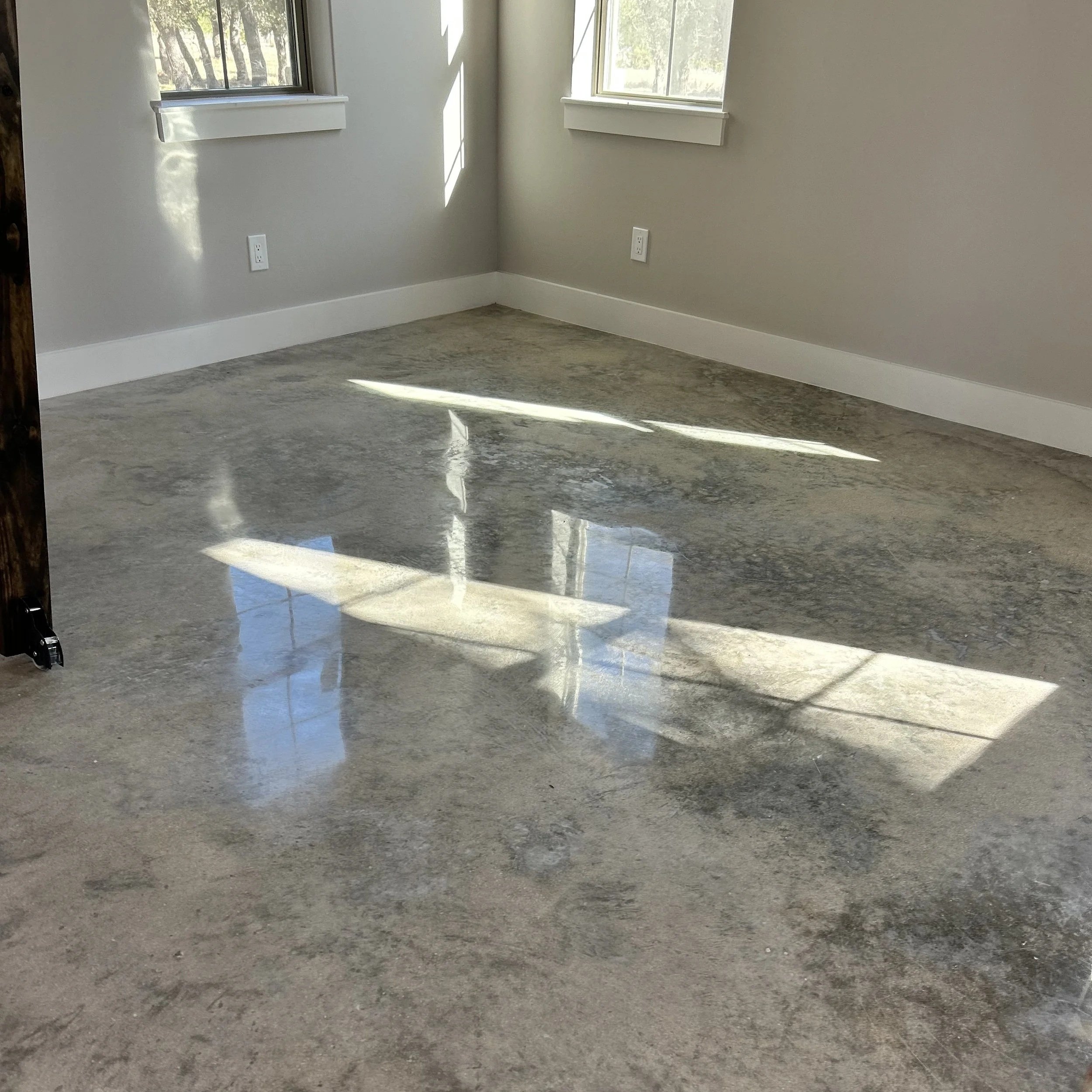 A small room with grey walls, white trim, and polished concrete for flooring.