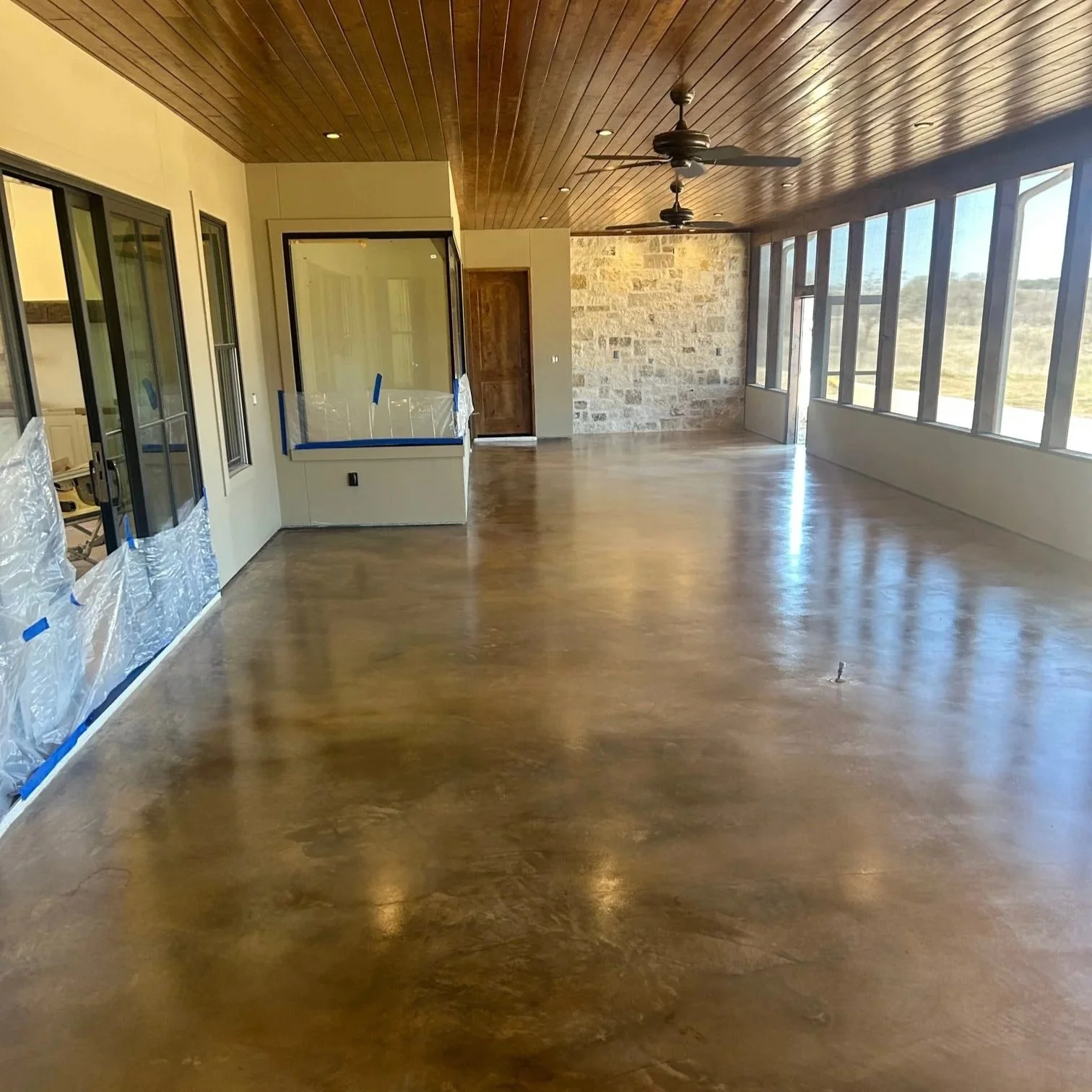 The screened in back porch of a home near Hext, TX that has newly refinished concrete floors.