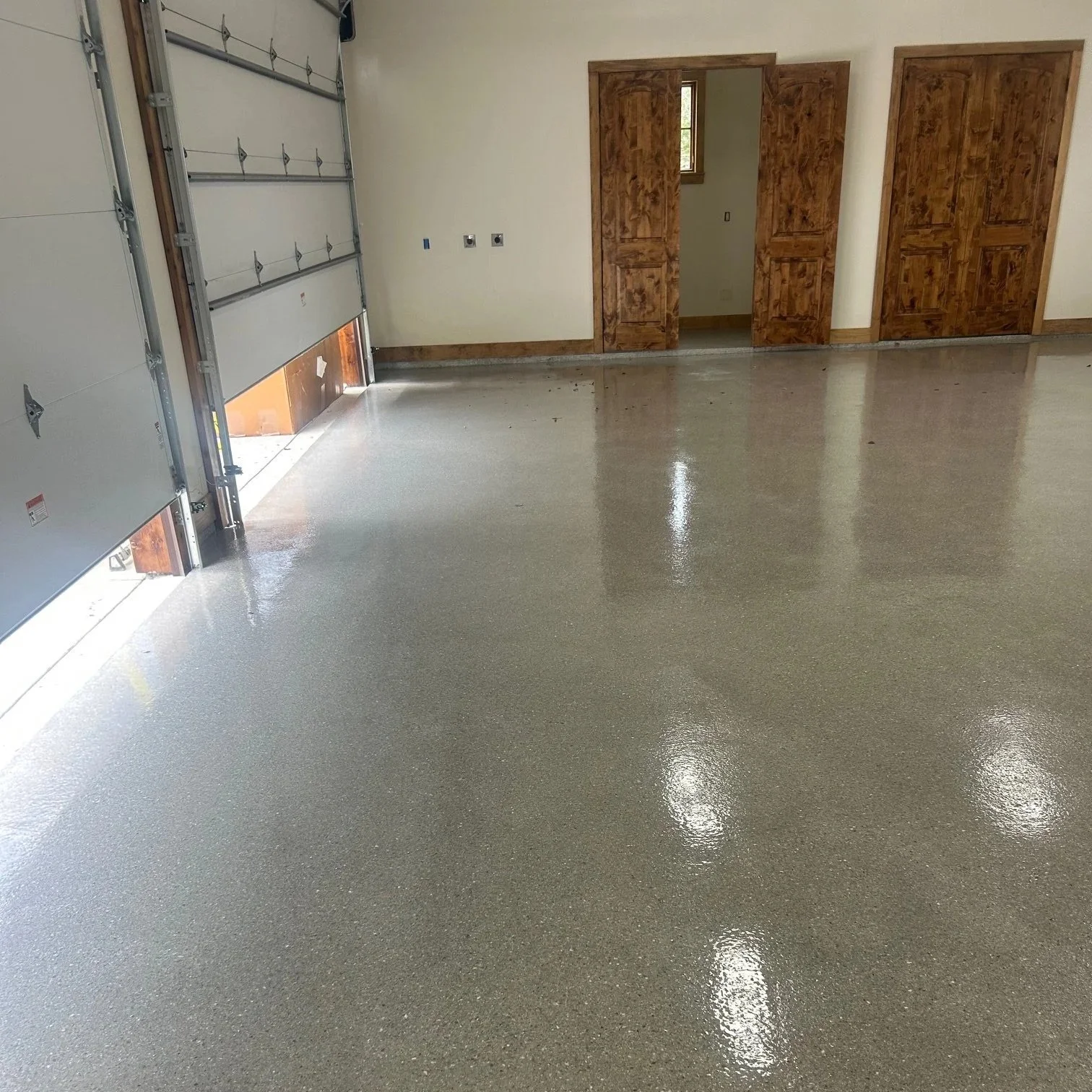 A garage with a newly refinished concrete floor that utilizes a resinous coating in grey.