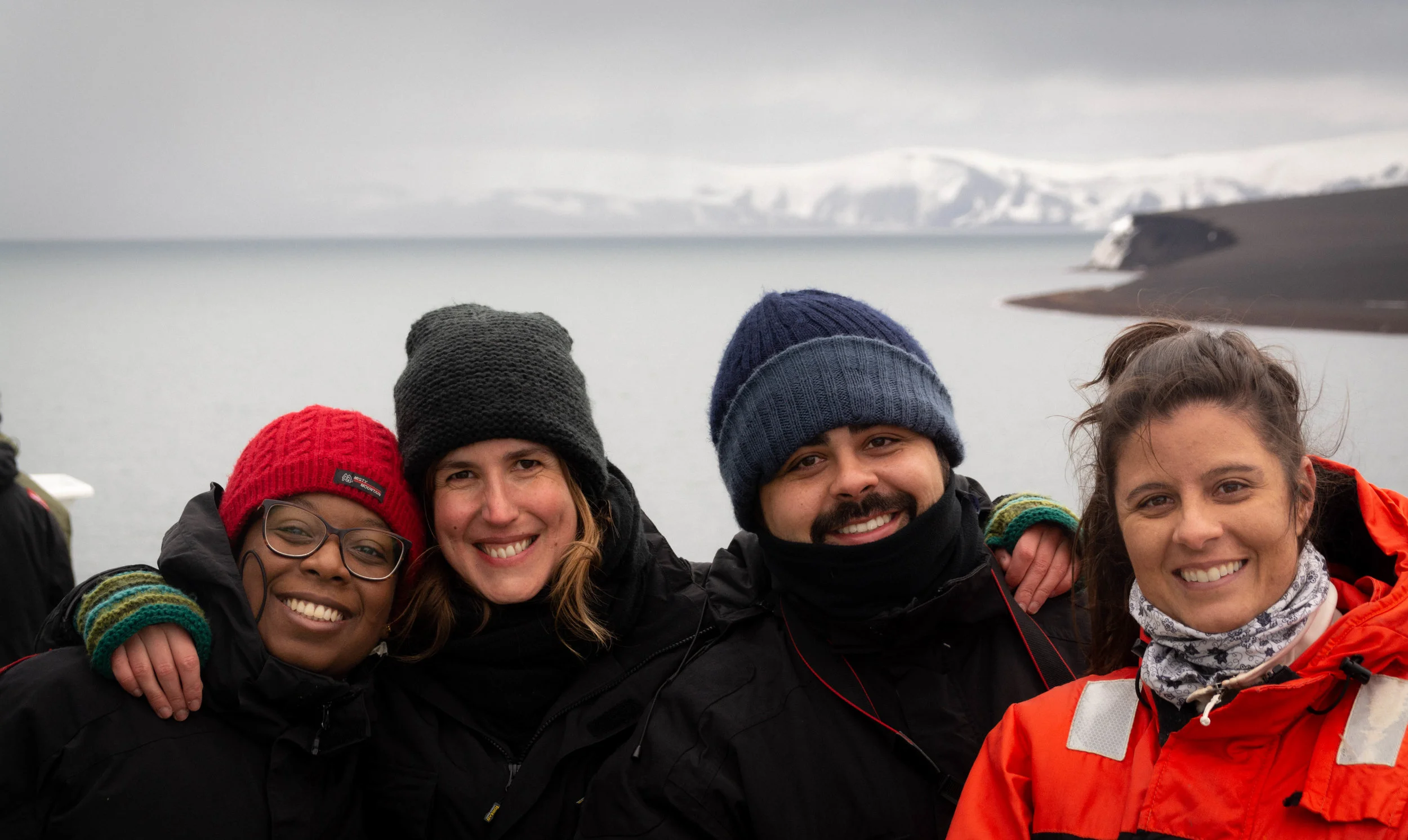 Happiness on board, with Deception Island in the background. From left to right: Raquel Avelina (oceanographer, State University of Rio de Janeiro), Catarina Guerreiro (Marine Geologist, MARE-FCiências.ID), Renan Lima (oceanographer, FURG) and Camila Signori (oceanographer, University of São Paulo).