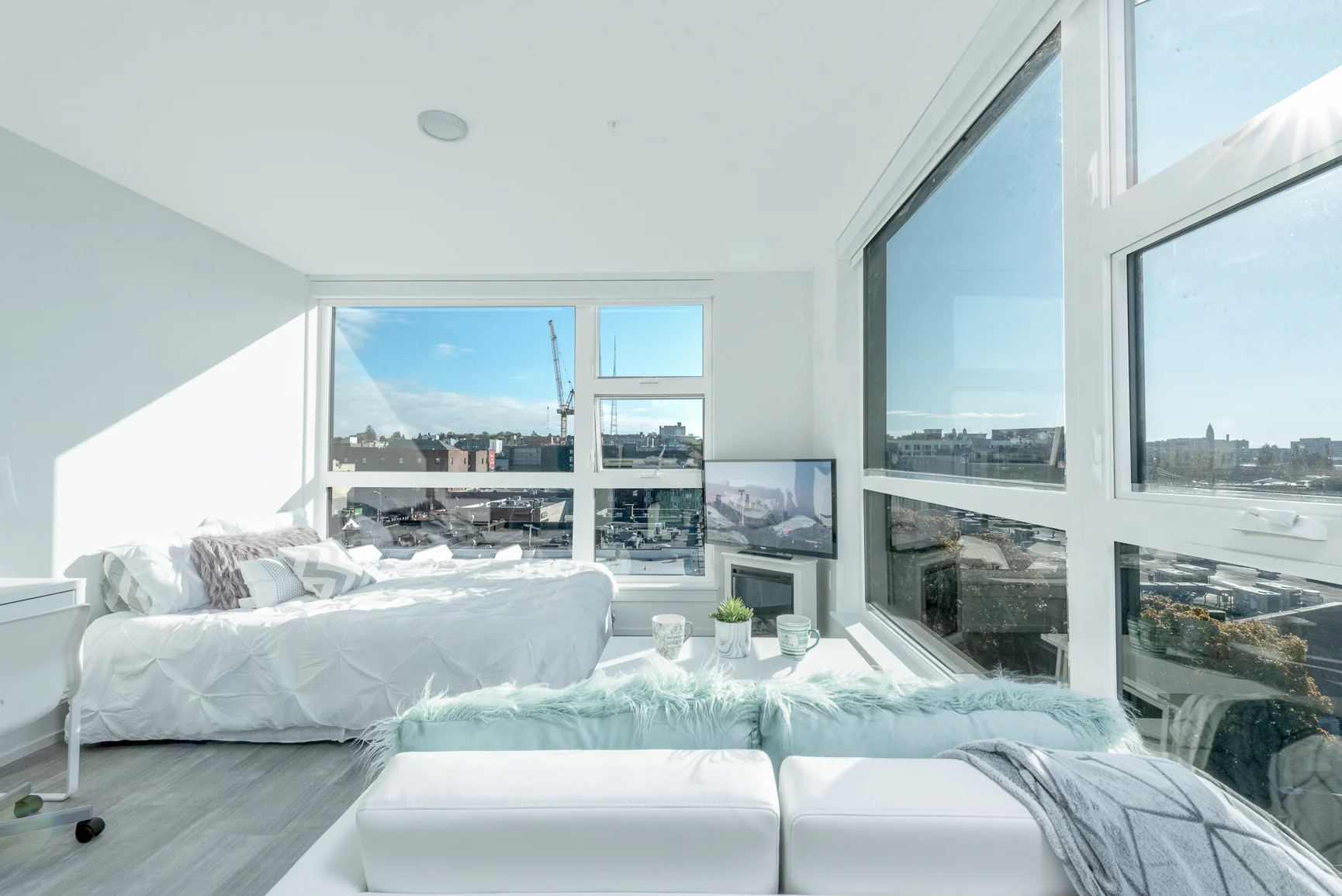 Studio bedroom at Pike Flats with large windows and white furniture