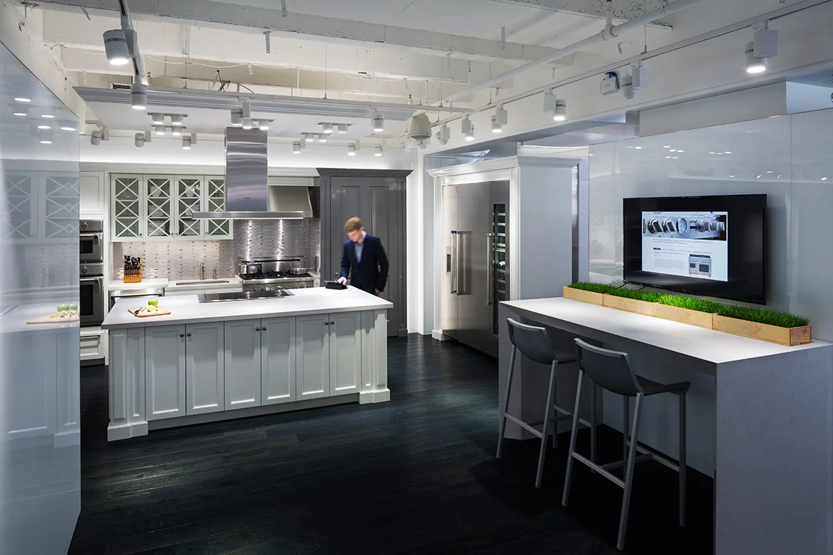 Man in a blazer viewing a tablet on a kitchen counter in the showroom of BSH, located in New York. MEP designed by 2L Engineering.