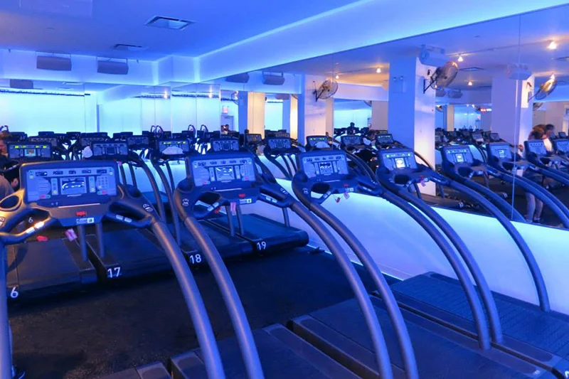A running studio at the Mile High Run Club with accented blue lighting and rows of treadmills for clients. MEP provided by 2L Engineering.