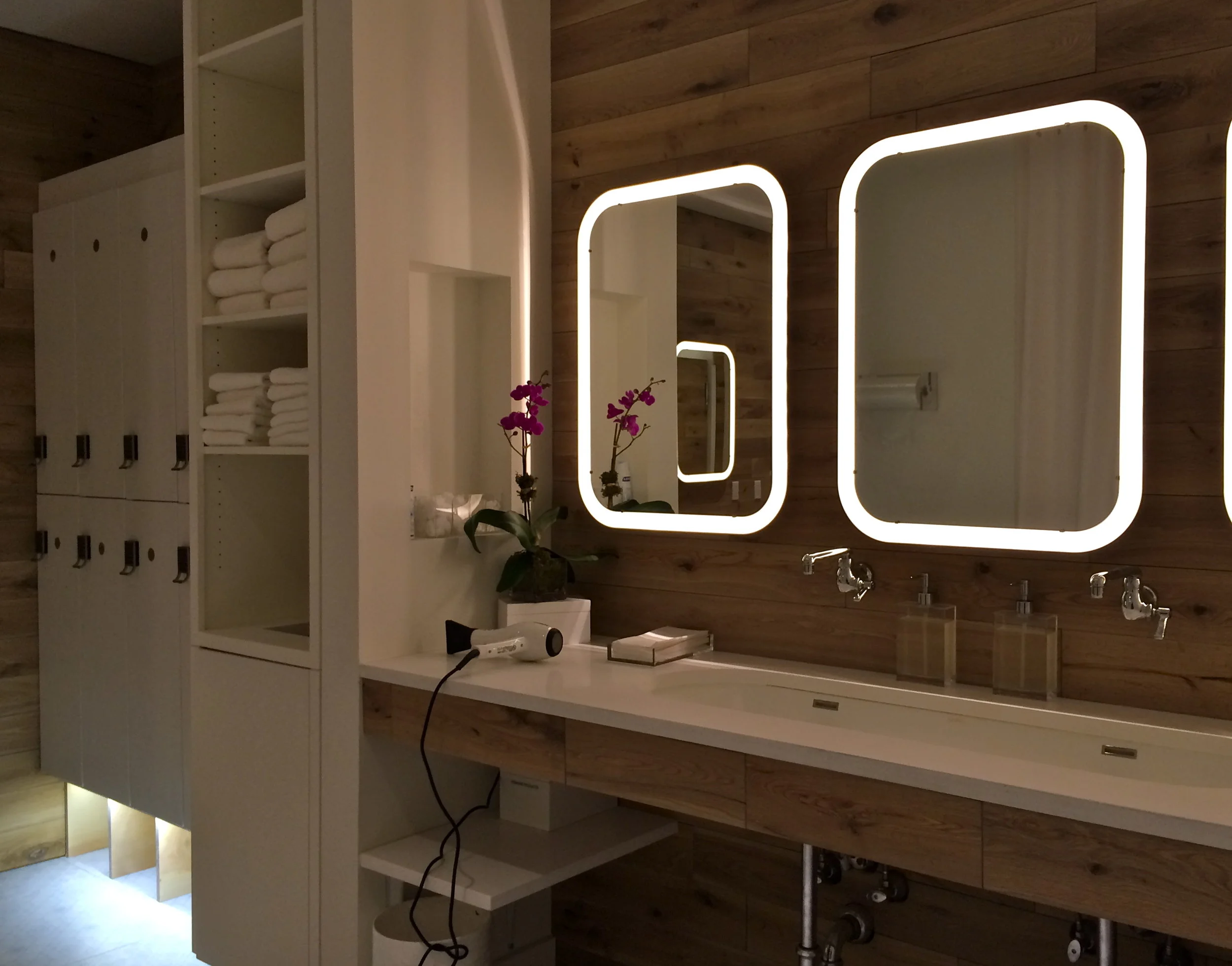 Locker room in the Mile High Run Club with orchids, complimentary towels, mirrors with frame lighting and storage spaces. MEP designed by 2L Engineering.