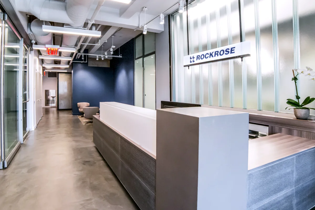 Reception area of Rockrose with minimalistic, modern design and the company's name featured above the desk. MEP designed by 2L Engineering.