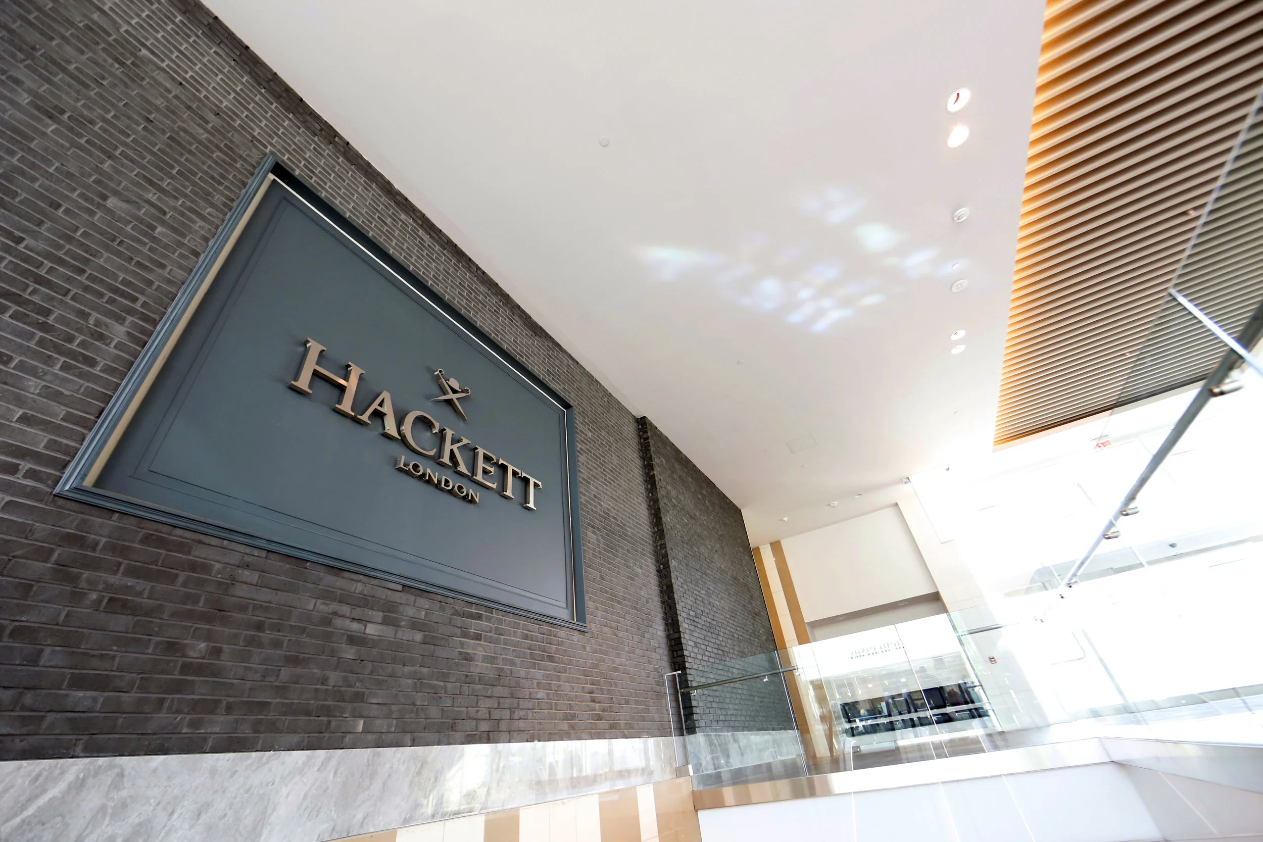 Dark grayish blue exterior signage of Hackett London in Woodbury Common Premium outlet. MEP designed by New York firm, 2L Engineering.