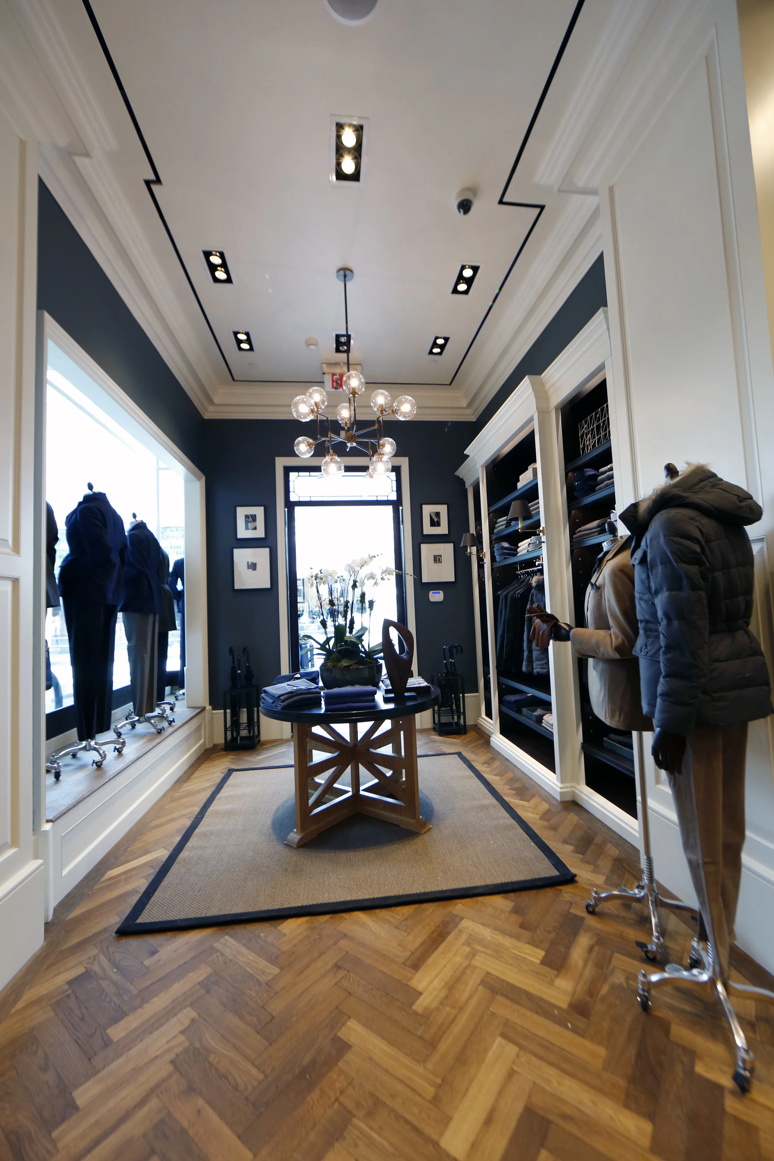 Orchids on a display table with collared shirts, a book, and brown leather loafers in Hackett London's Woodbury Common Premium outlet location. MEP by New York firm, 2L Engineering