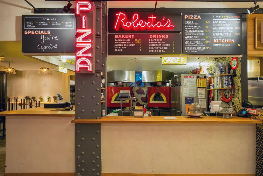 Roberta's Pizza, featuring neon red signs and pizza ovens, in Urbanspace Vanderbilt near Grand Central Terminal. MEP provided by 2L Engineering.