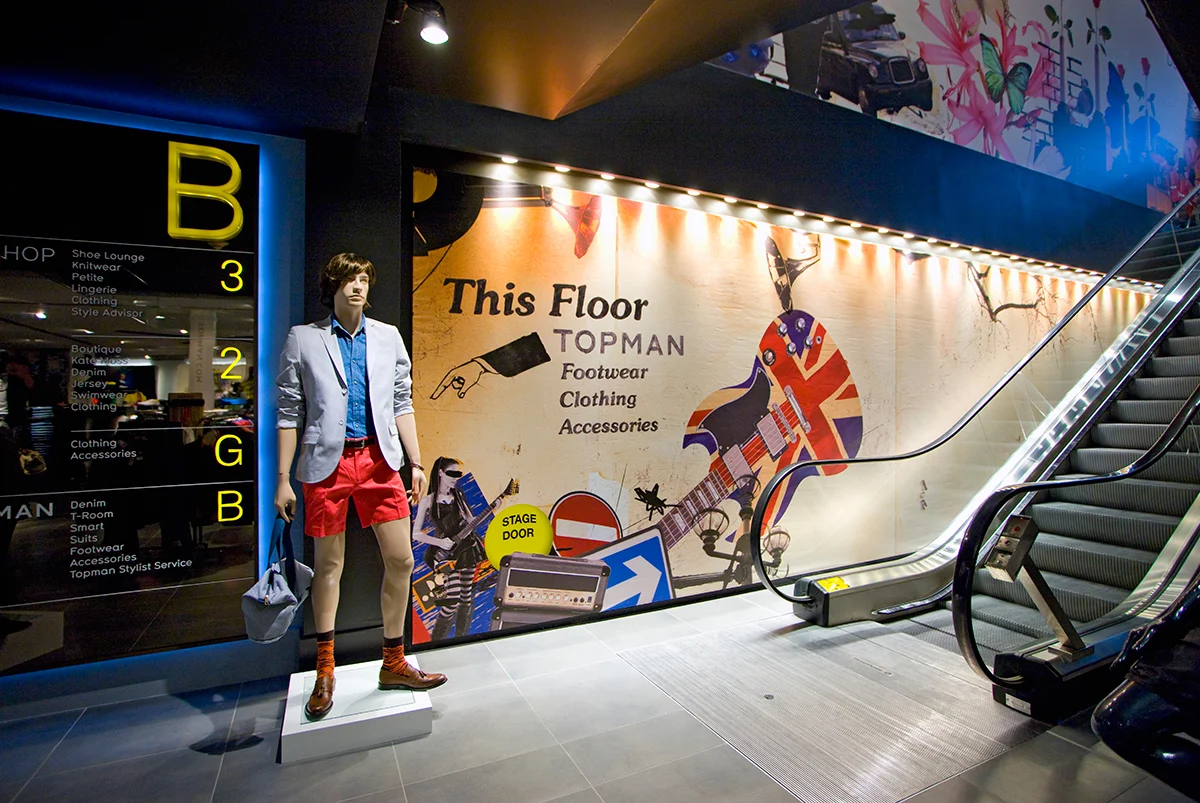 Mannequin dressed in trendy mens clothes standing by the escalators of the Topshop / Topman store in New York. MEP design services by 2L Engineering.