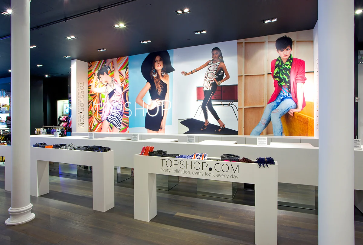 Cash registers and small display racks with large pictures of female models wearing Topshop clothing. MEP provided by 2L Engineering.