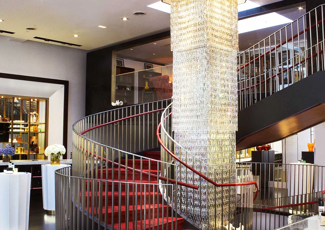 Spiral staircase with red carpeting and red handles, featuring an ornate center in Institute Erno Laszlo Skincare, a luxury skincare retail store and spa in Soho, New York. MEP by 2L Engineering.