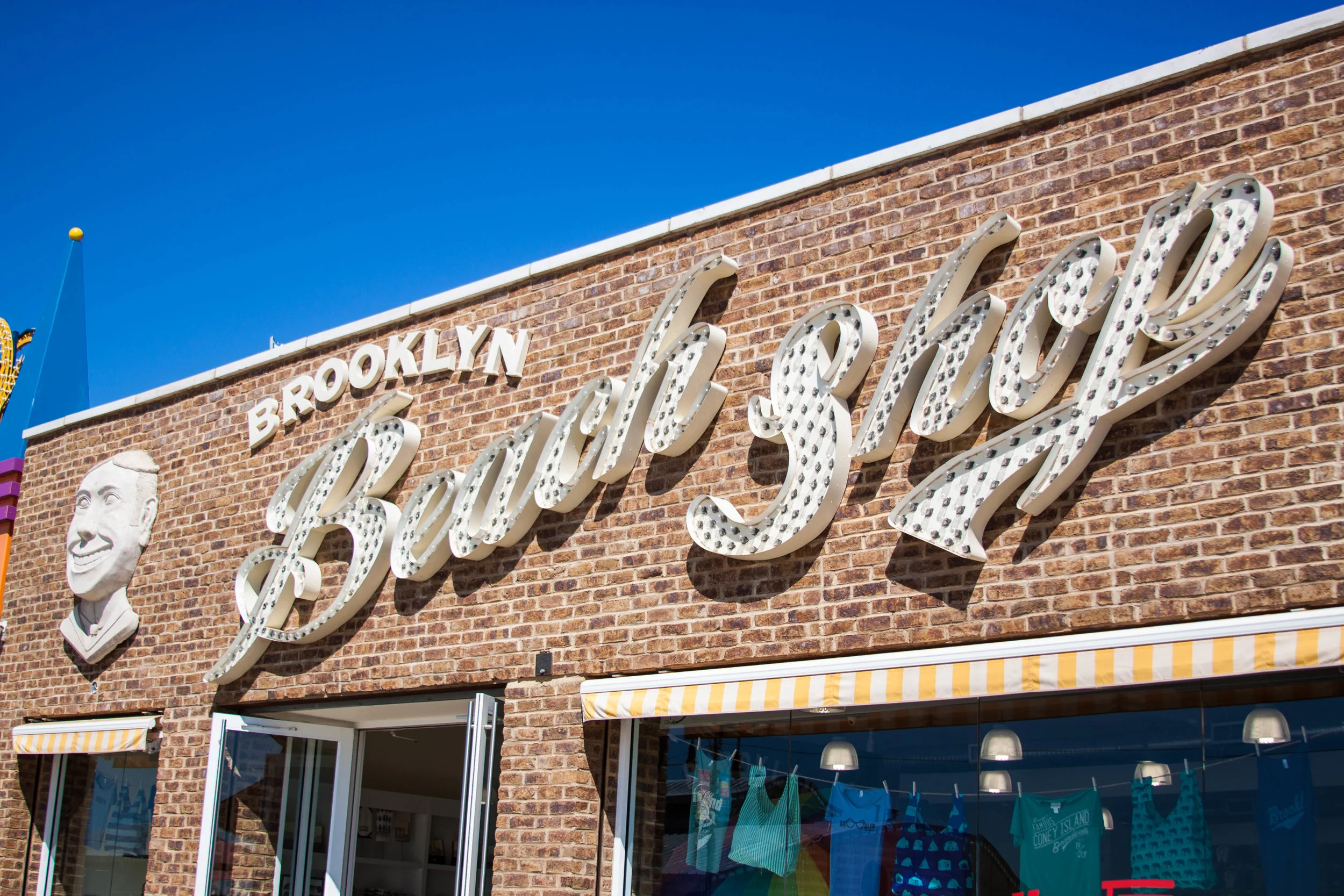 Vintage signage on the brick wall exterior of the Brooklyn Beach Shop, a retail space on the Coney Island Boardwalk with a new facade. MEP designed by 2L Engineering.