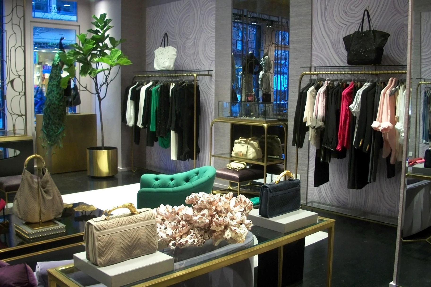 Clothing rack with designs from Monika Chiang and handbags on display in front of a geode-like wallpaper. MEP designed by 2L Engineering.