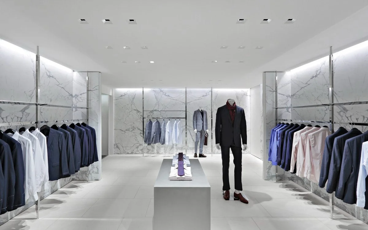 Sharply dressed mannequins in the menswear section of Barney's New York surrounded by clothing racks and a minimalistic interior. MEP designed by 2L Engineering.