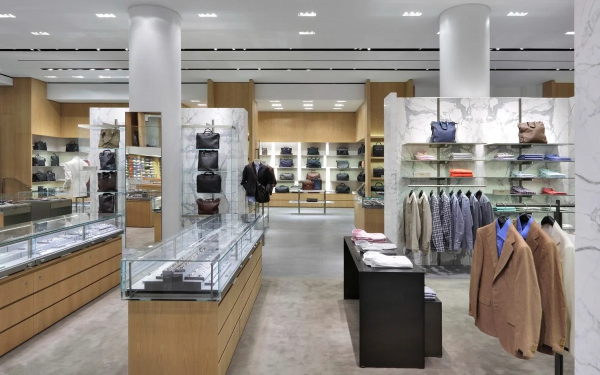Mens accessories in display cases, bags on display shelves, and blazers for customers to browse in Barney's New York department store. MEP designed by 2L Engineering.