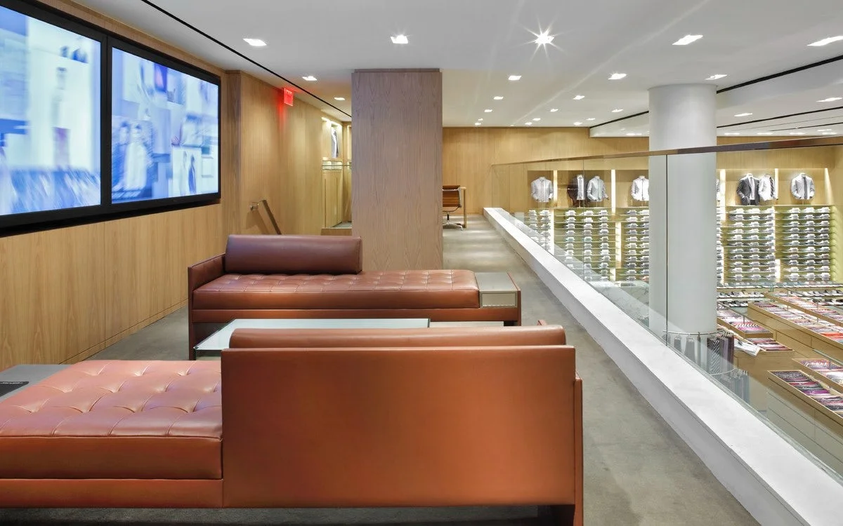 Leather brown couches in a seating area with screens showing the lastest from Barney's New York catalogue. MEP designed by 2L Engineering.