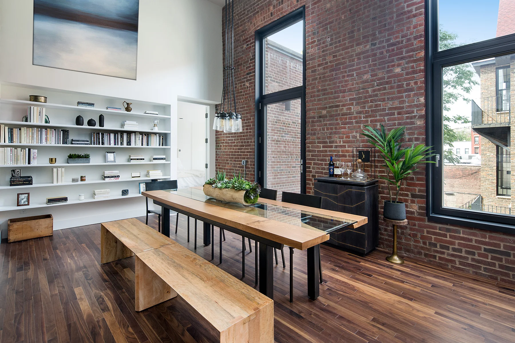 Dining area with a rustic flare mixed with modern design, a bookshelf and brick wall in a Brooklyn apartment. MEP provided by 2L Engineering.