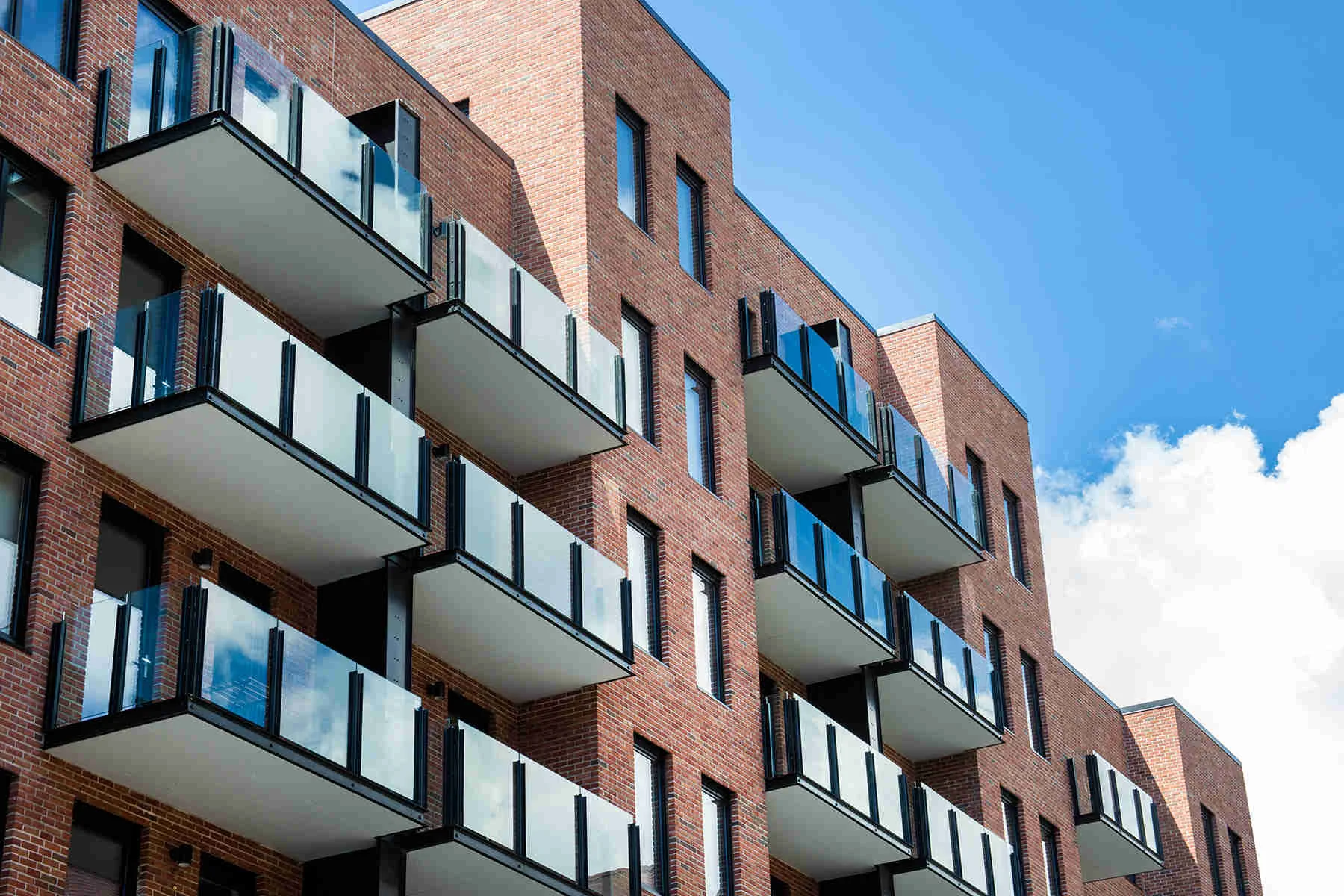 Balconies with glass railing on a residential building with a brick exterior in Brooklyn, New York. MEP designed by 2L Engineering.