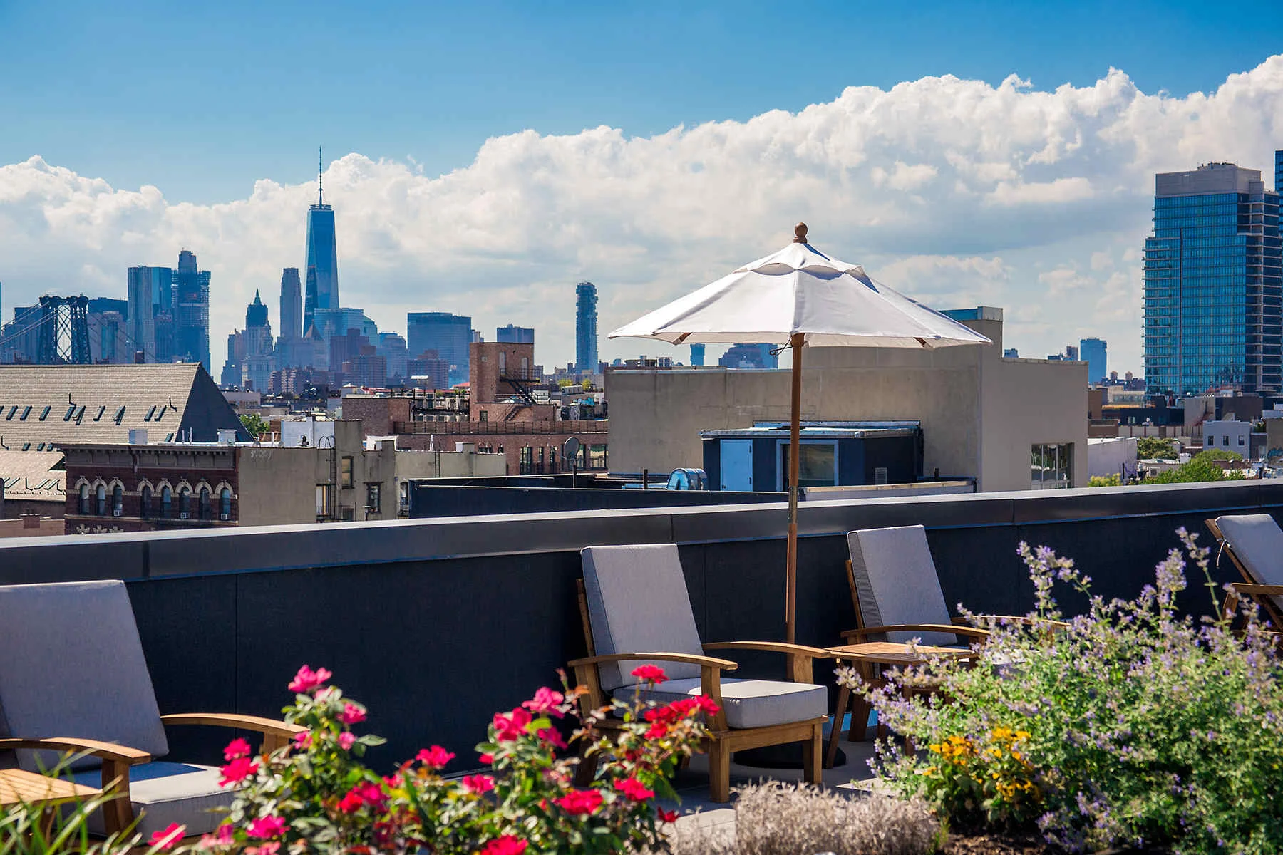 Rooftop with seating and umbrellas on a Brooklyn residential building facing the Manhattan skyline. MEP designed by 2L Engineering.