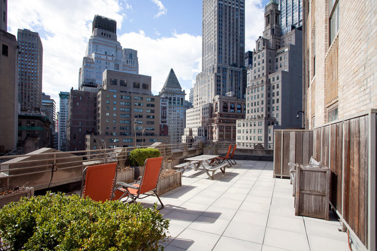 Seating area on the balcony of a luxury apartment building overlooking the New York skyline. MEP designed by 2L Engineering.