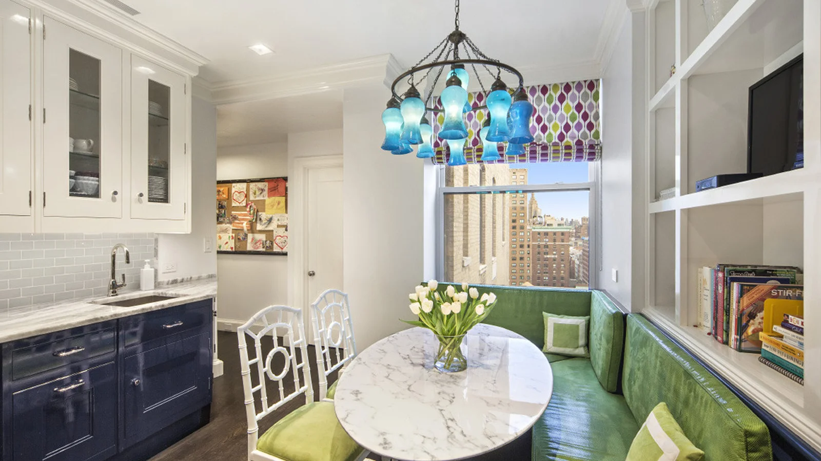 Breakfast nook with lime green seating and a light blue chandelier facing dark blue kitchen cabinets. MEP designed by 2L Engineering.