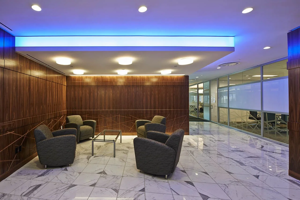 Lounge area with geometric designs on the wooden wall pannels and blue mood lighting at the offices of Wood Mackenzie in New York. MEP designed by 2L Engineering.