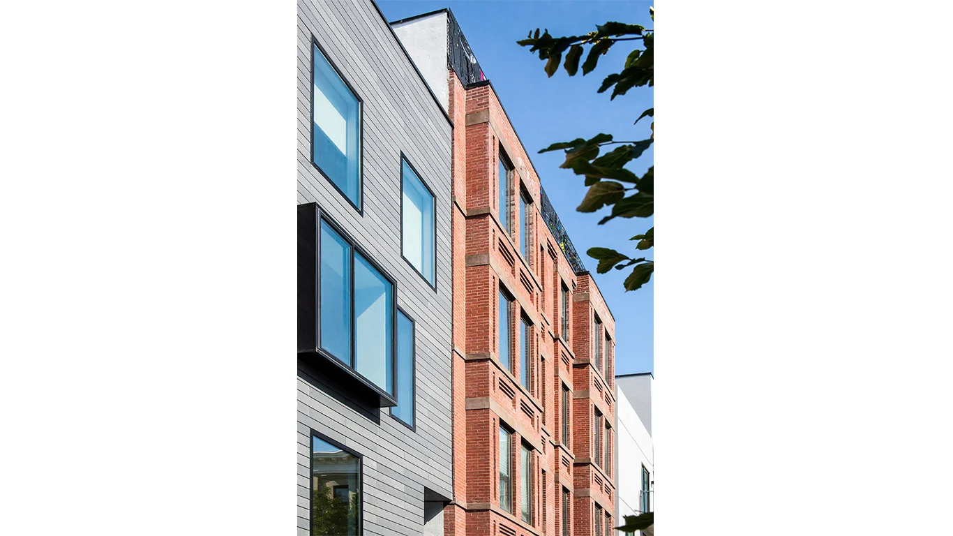 Brick and wood facade of a residential building in Brooklyn facing the sidewalk. MEP provided by 2L Engineering.