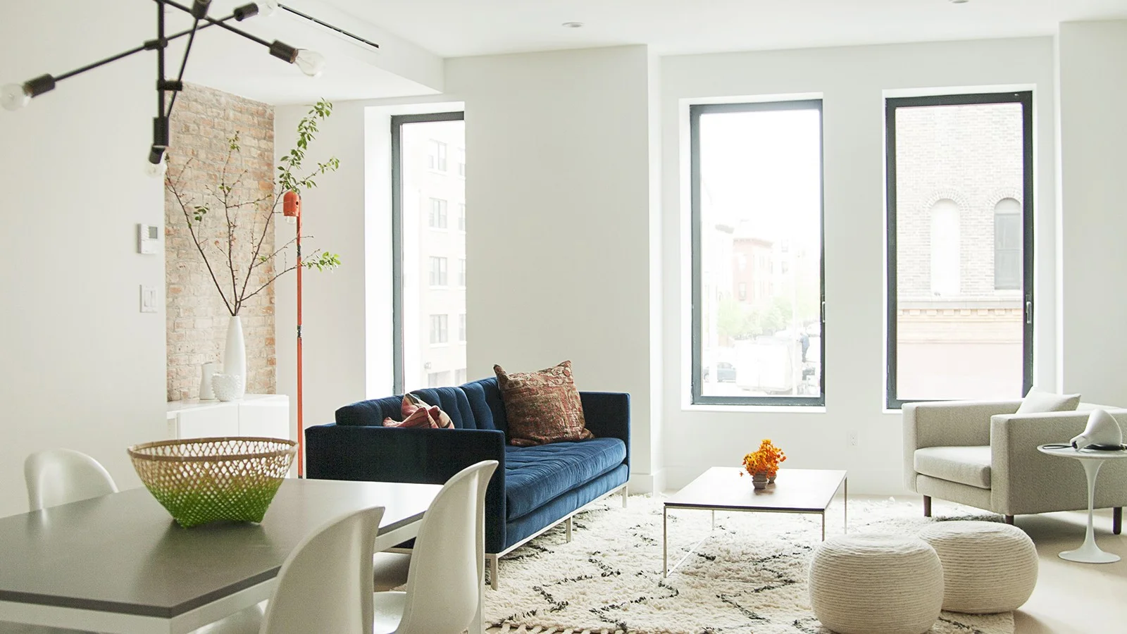 Large windows looking into a Scandinavian style living room with a big navy blue couch in a luxury residential home in Brooklyn. MEP by 2L Engineering..