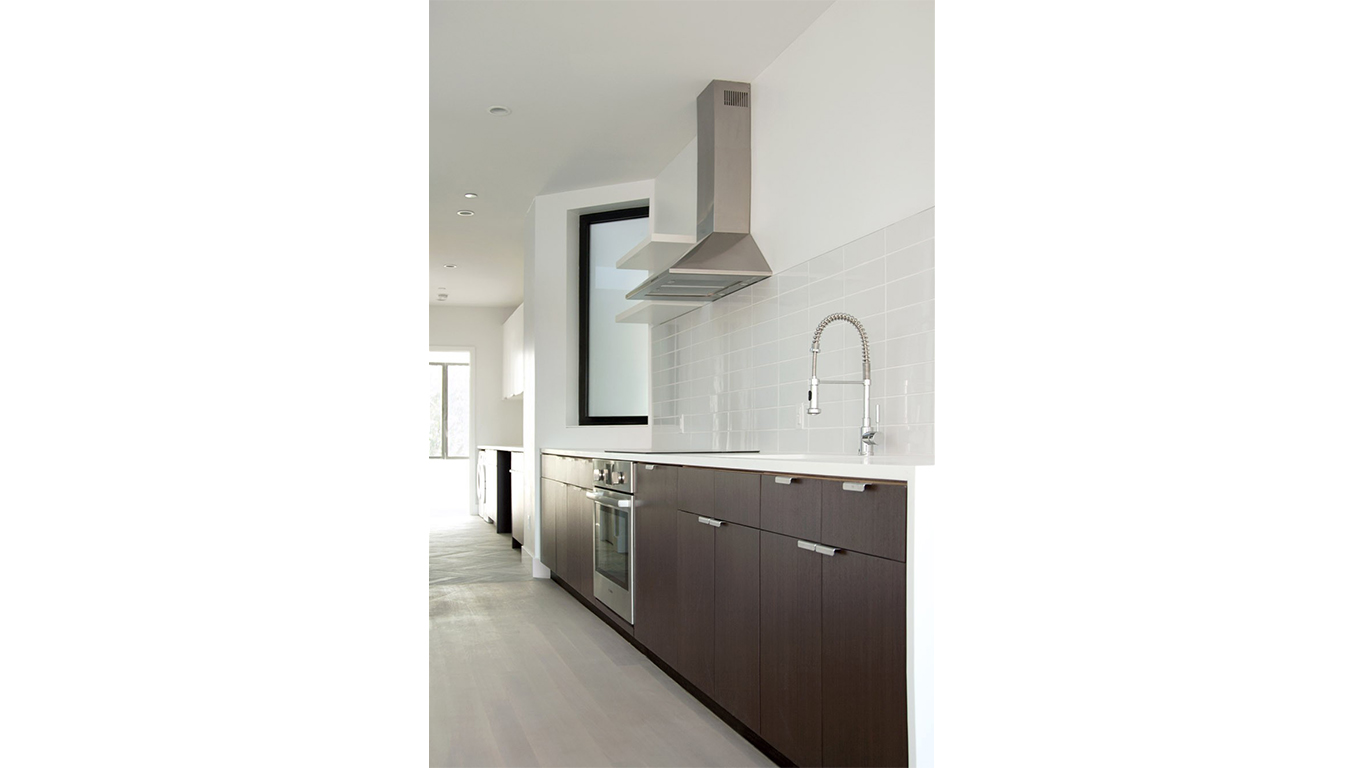Luxury kitchen with a minimalistic design and dark wood cabinets. MEP provided by 2L Engineering.