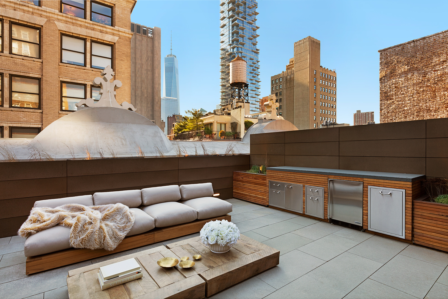 Lounge area with bar, sofa, and coffee table on the rooftop of a luxury residential building surrounded by New York skyscrapers. MEP designed by 2L Engineering.