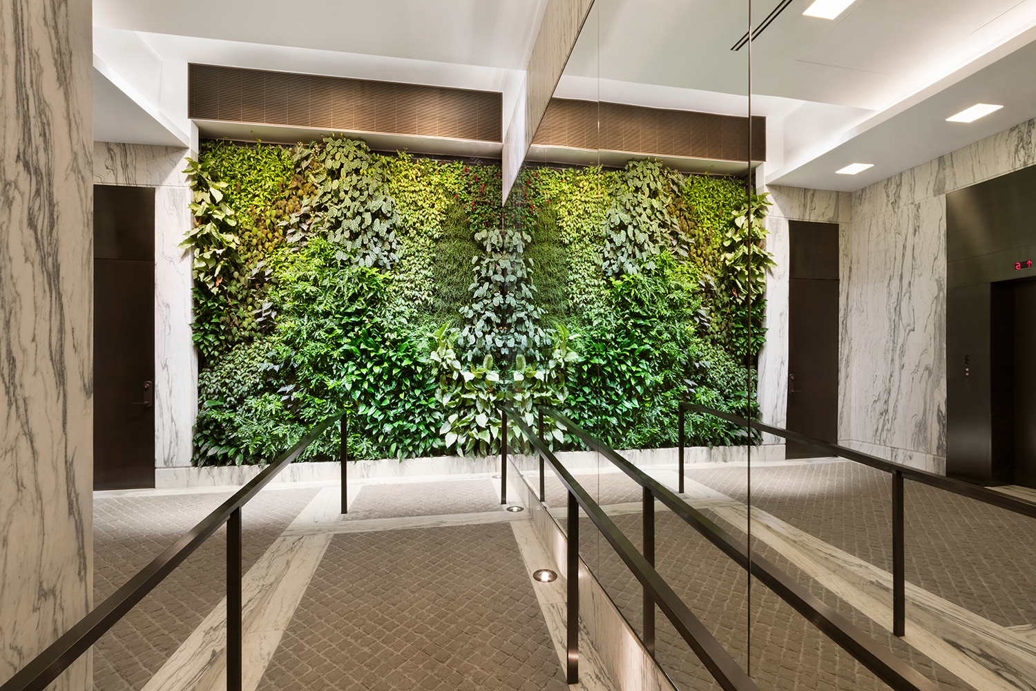 Front perspective of a living green wall beside large mirrors inside the lobby of a luxury residential building. MEP designed by 2L Engineering.
