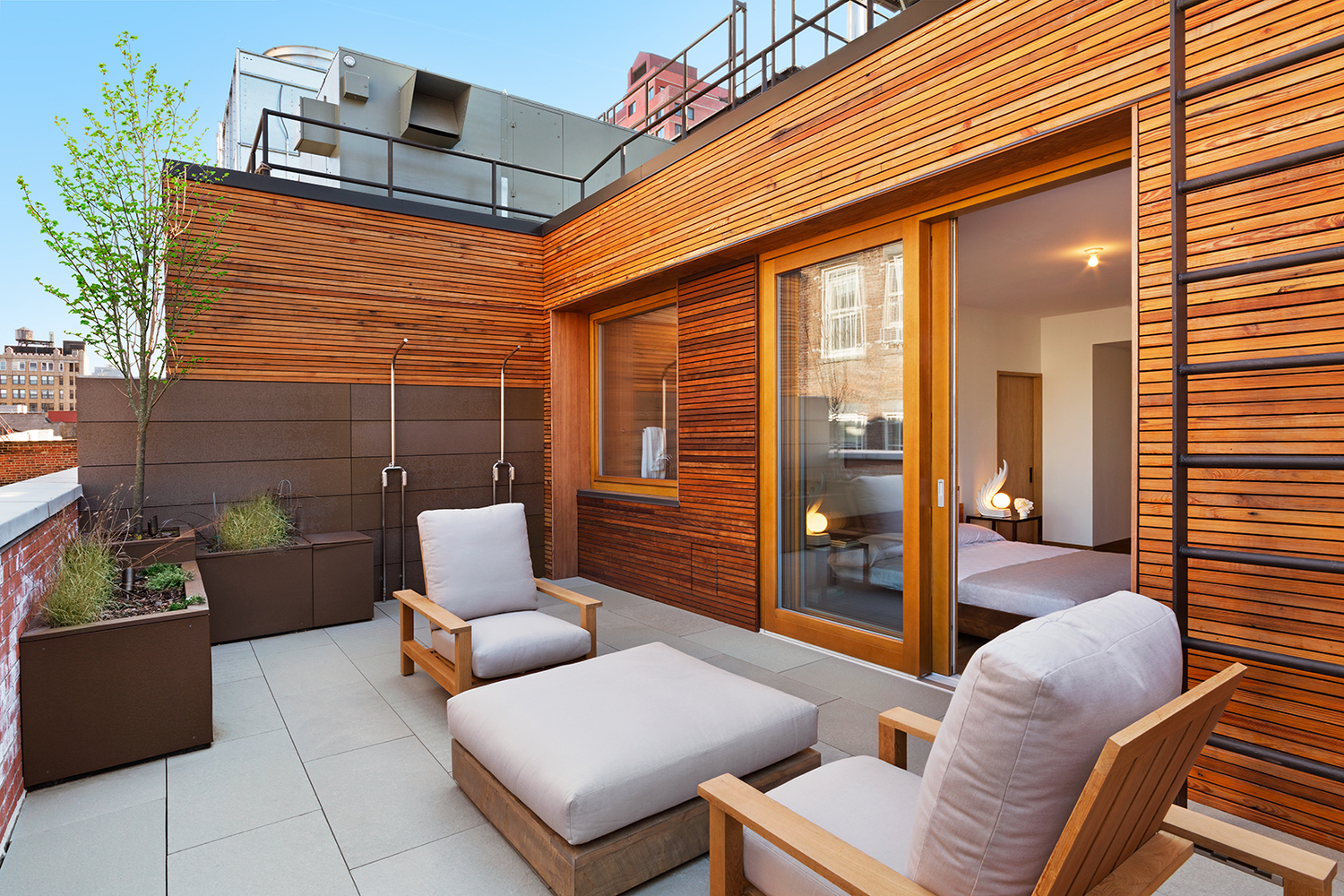 Outdoor lounge area beside doors leading to a bedroom, featuring wood panelled walls. MEP designed by 2L Engineering.