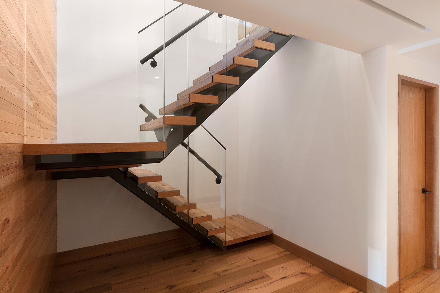 Wooden staircase with glass railing inside a luxury apartment featuring MEP work done by New York firm, 2L Engineering.