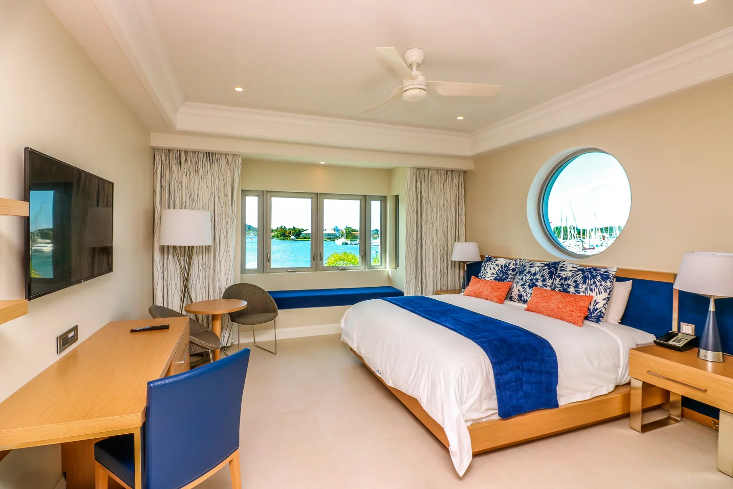Harbor Club Hotel guest bedroom with blue accents and wood furniture overlooking the harbor at St. Lucia. MEP designed by 2L Engineering.