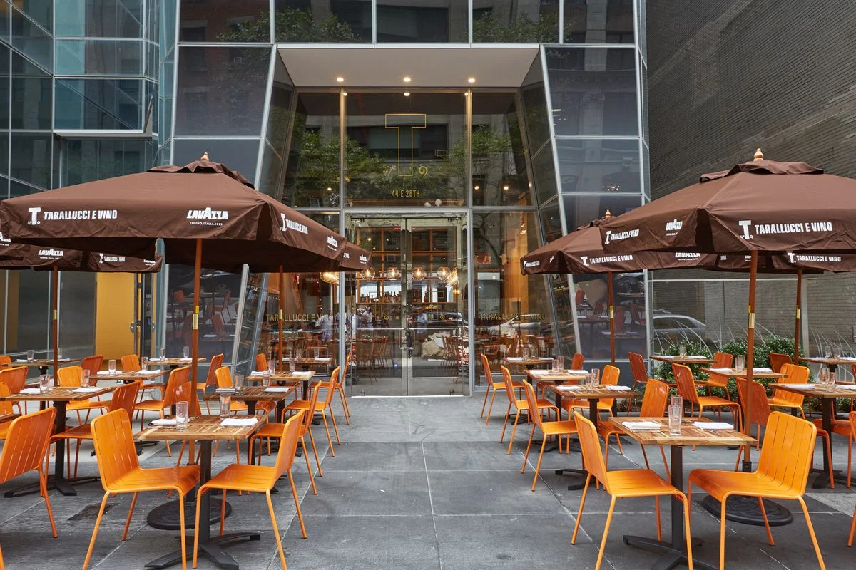 Orange outdoor seating with brown umbrellas at Tarallucci e Vino on 44 East 28th Street, New York. MEP designed by 2L Engineering.