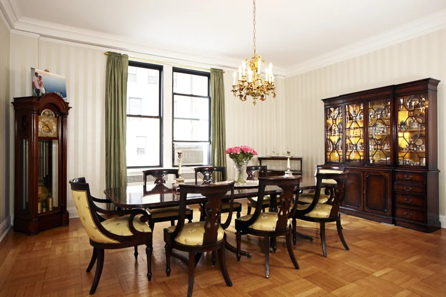 Dining room with antique furniture including a grandfather clock, candle chandelier, and a china cabinet. MEP provided by 2L Engineering.
