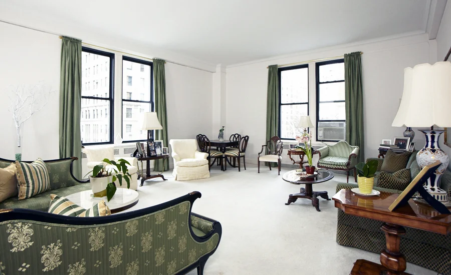 The lounge area of a Park Avenue apartment with green details such as forest green curtains, and printed green seating. MEP provided by 2L Engineering.