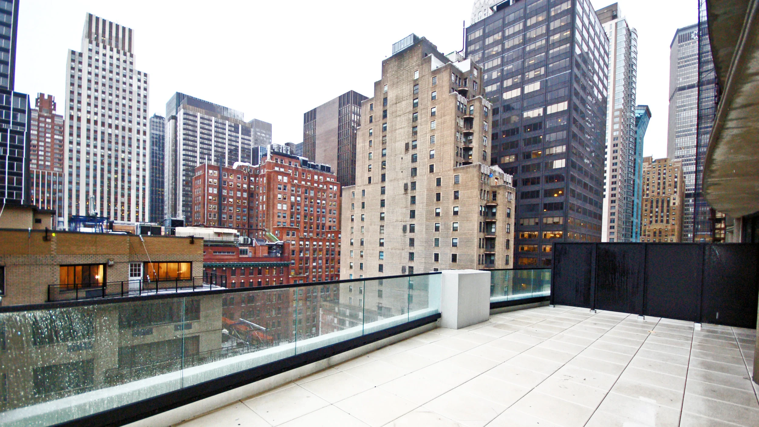 Rainy-day balcony view of New York City from a new mid-rise rental building in Midtown East. MEP designed by 2L Engineering.
