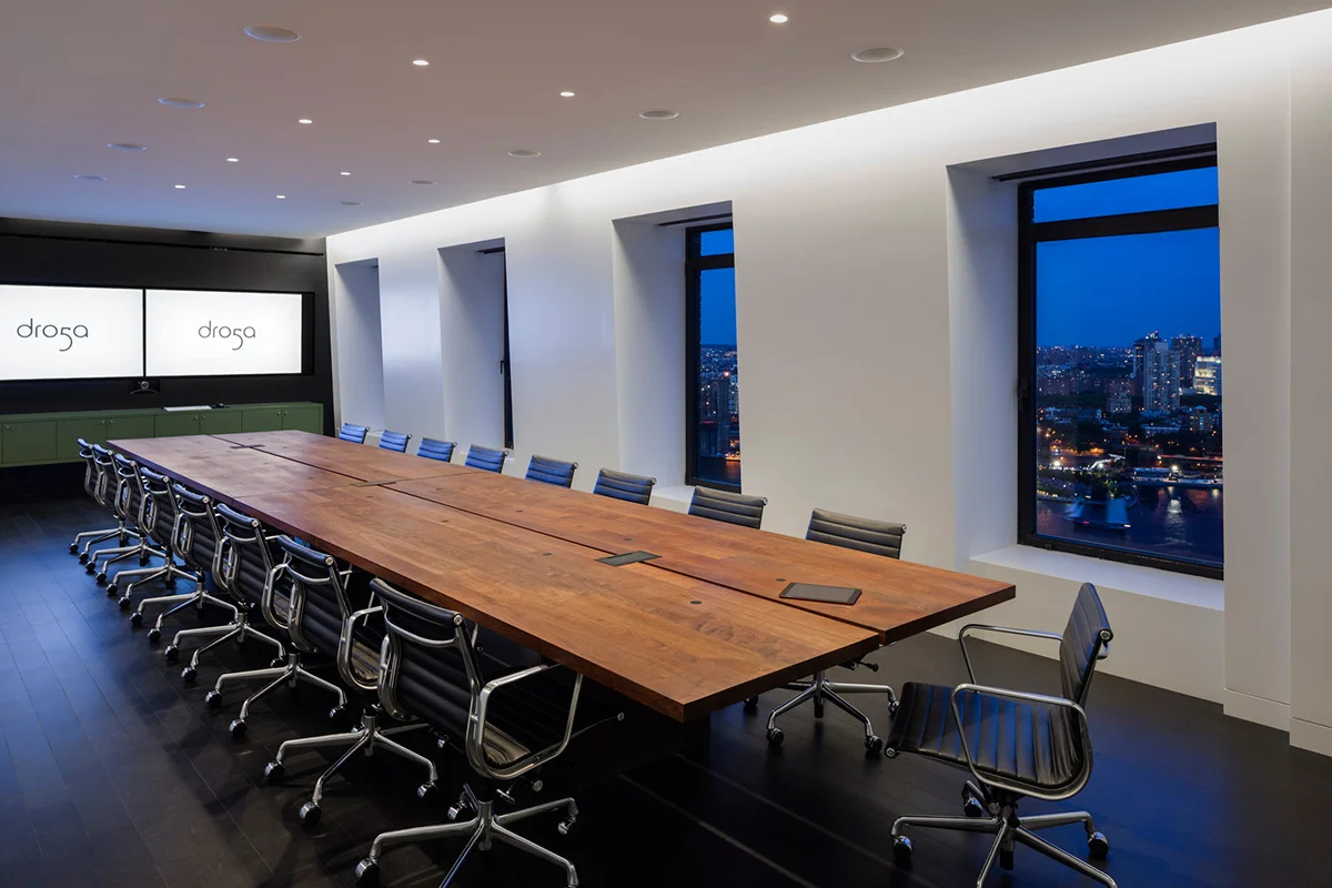 A large conference room with bright TVs showing the Dro5a logo and the New York skyline outside. MEP designed by 2L Engineering.