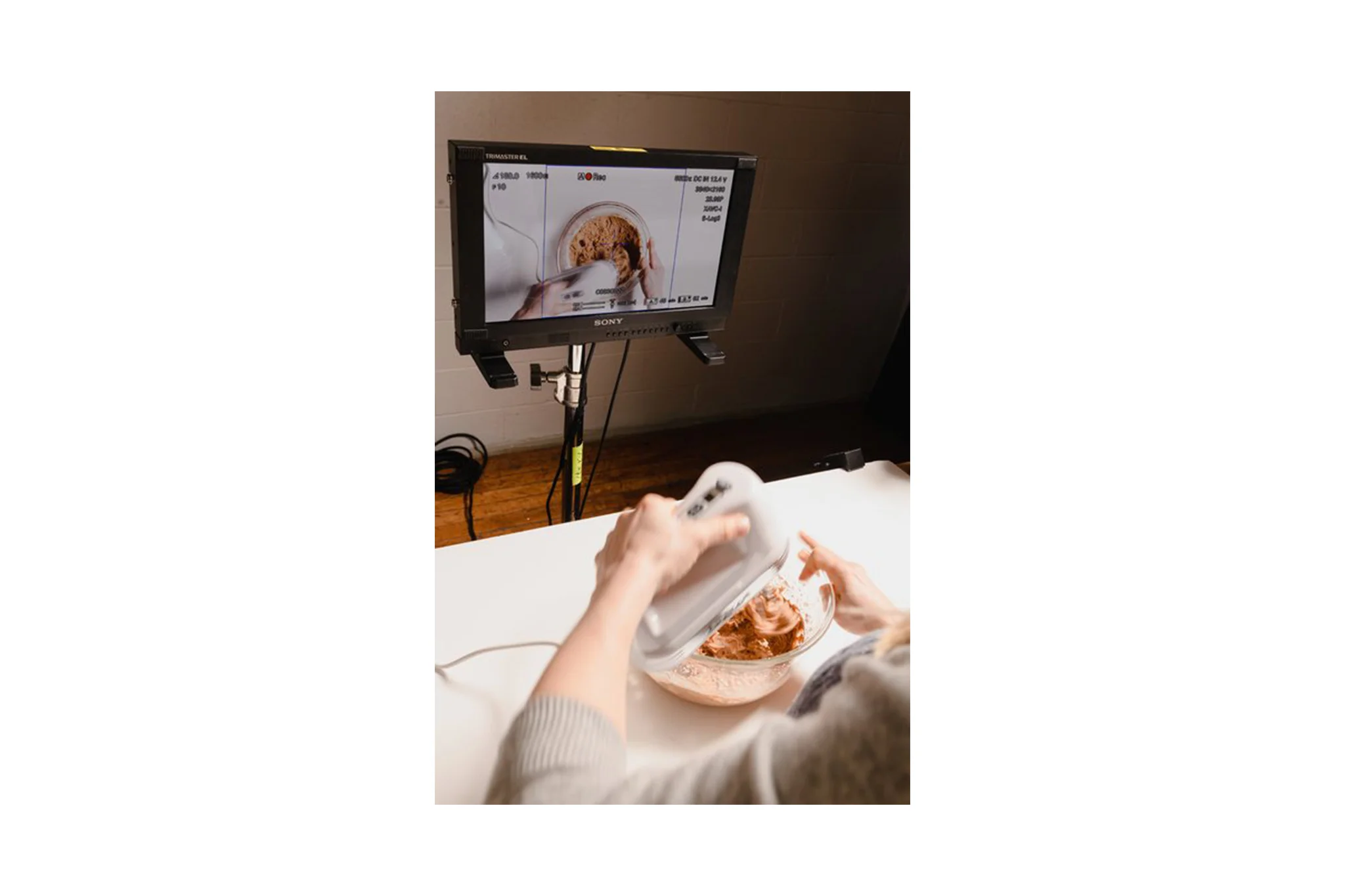 A person being filmed preparing baked goods in a small bowl in the prep kitchen of Conde Nast's studio in Brooklyn, New York. MEP designed by 2L Engineering.