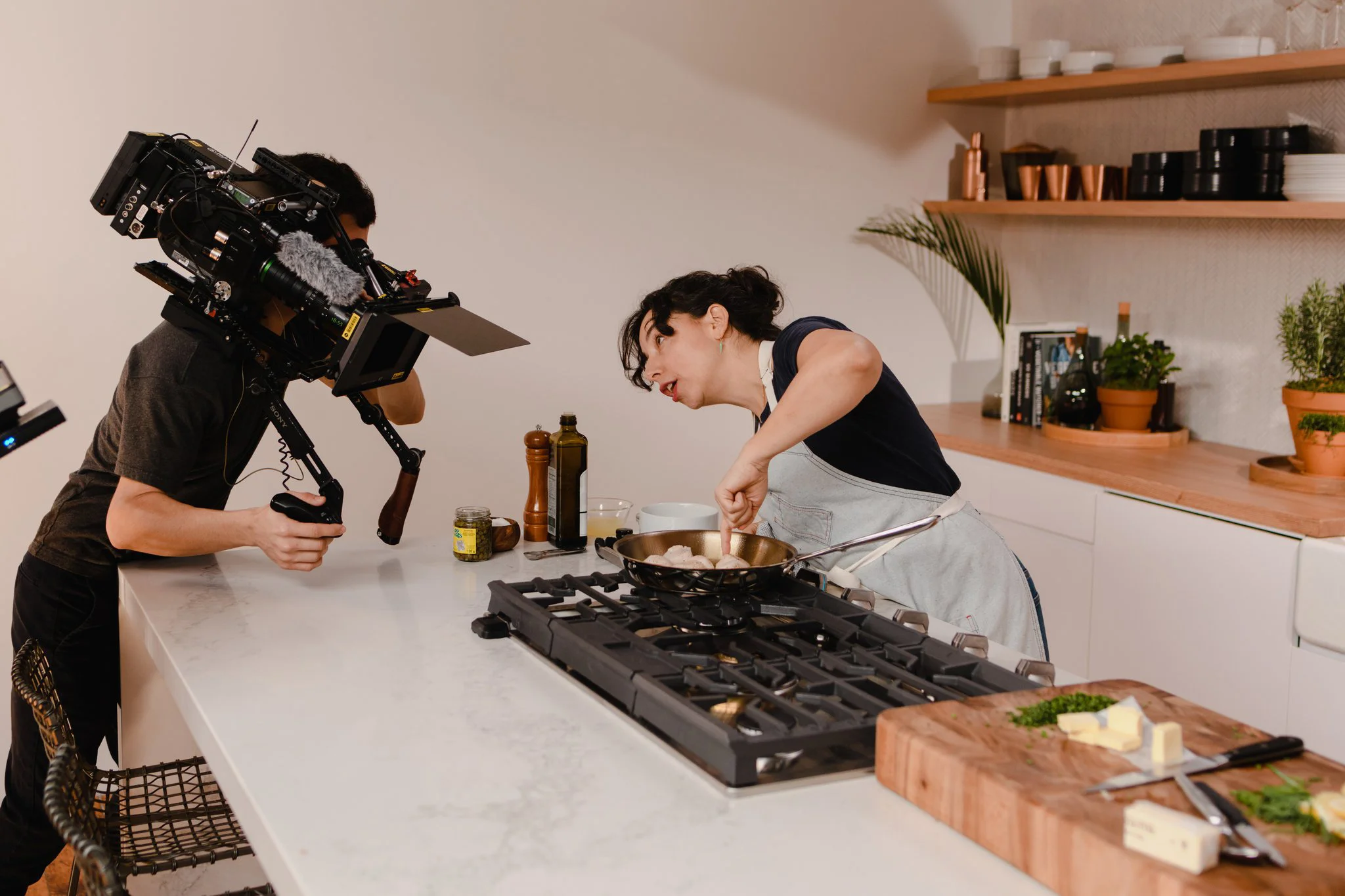 A woman looking into the camera as she points at mushrooms and explains her process in the kitchen studio of Conde Nast in Brooklyn, New York. MEP designed by 2L Engineering.