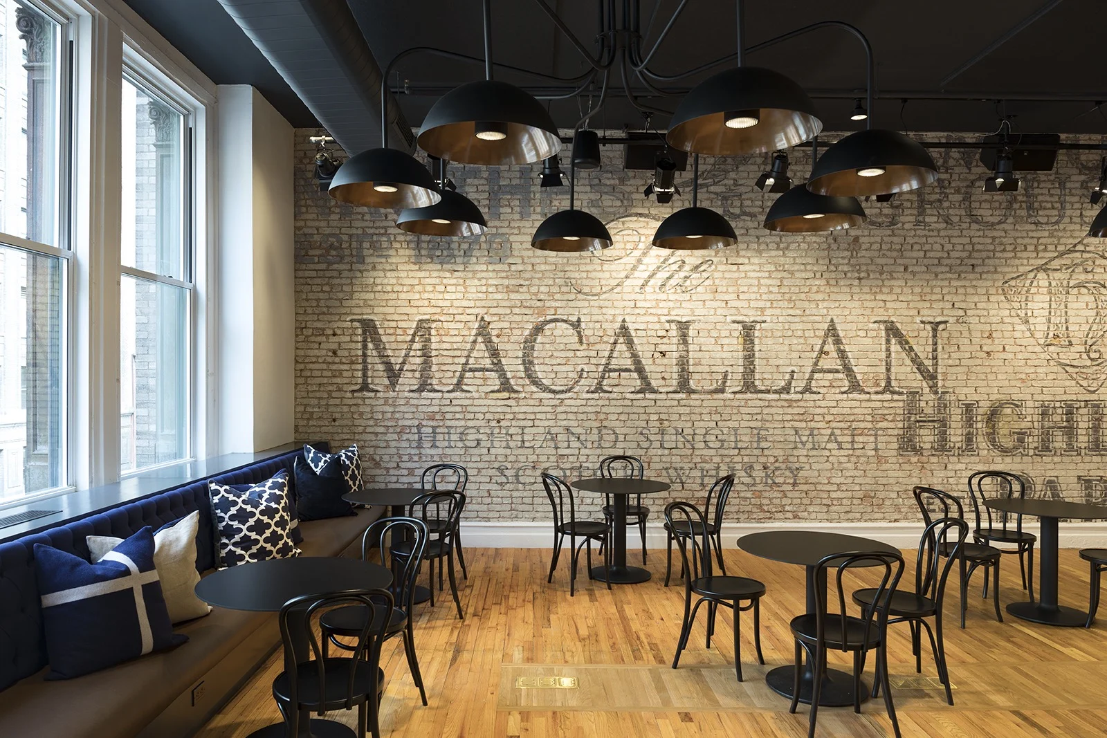 Black chairs and tables beside a brick wall with names of whiskey brands managed by Edrington Spirits. MEP designed by 2L Engineering.