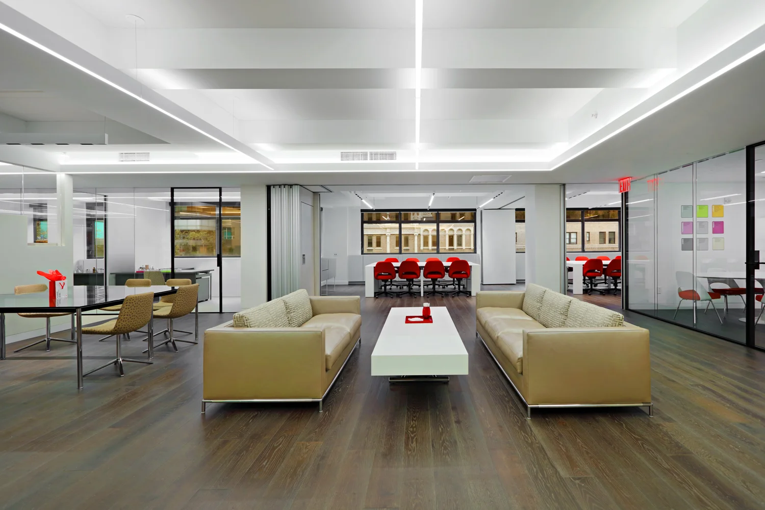 Lounge and break room surrounded by offices and conference rooms with red orange chairs at the Symrise office located in New York. MEP designed by 2L Engineering.