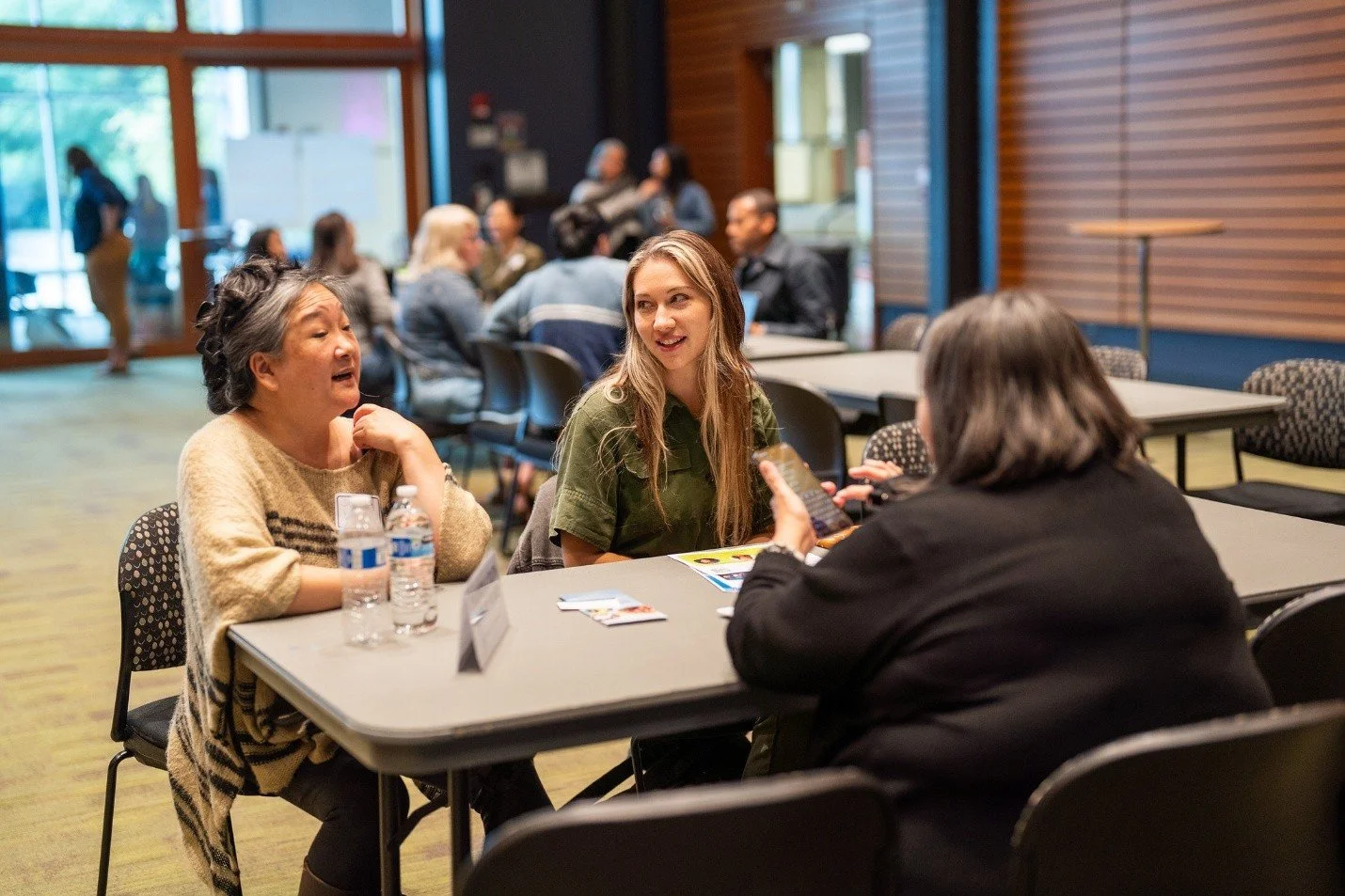 People seated around tables in a conference room talking to each other.