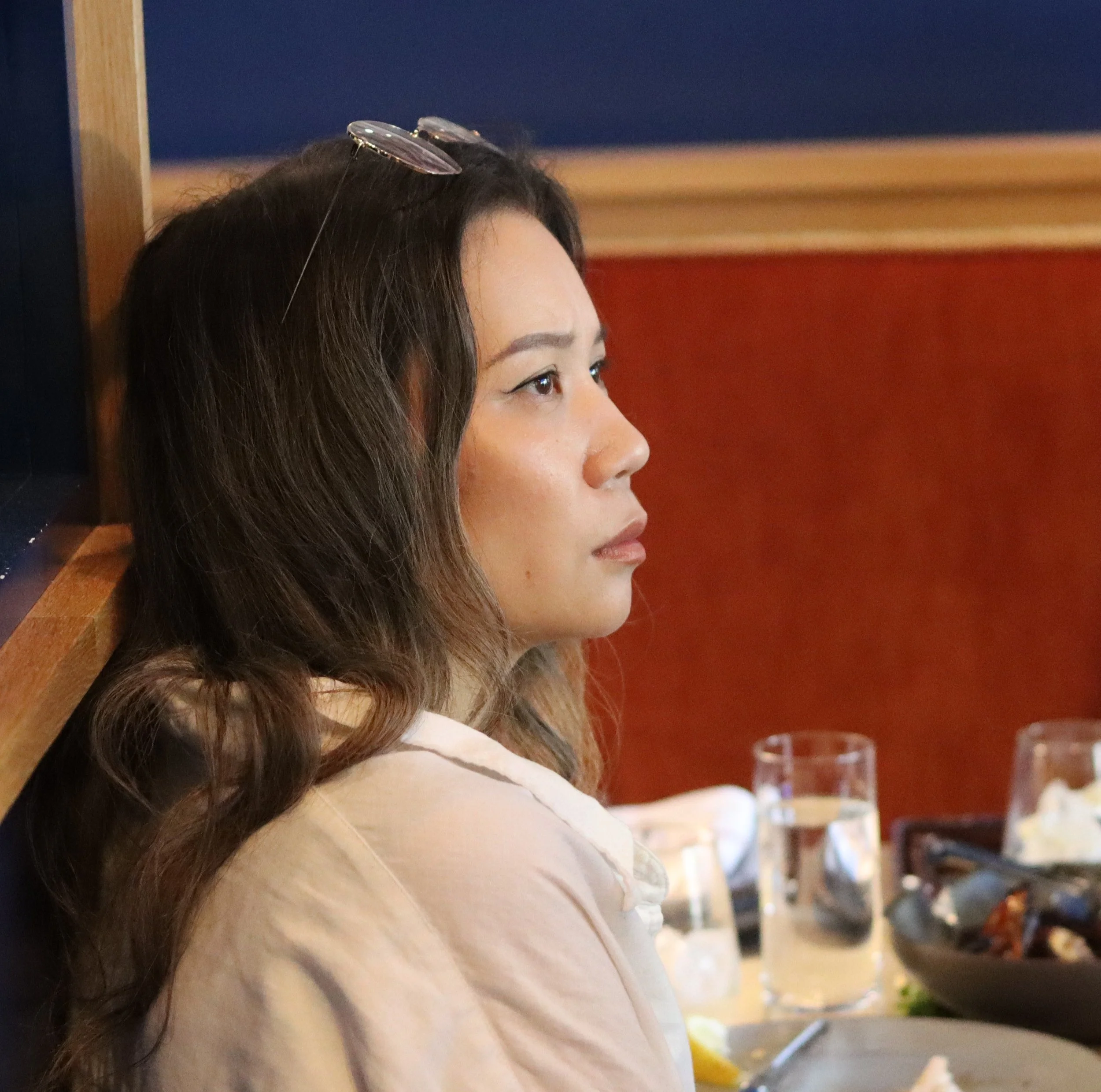 A person with long dark hair looks to their right
