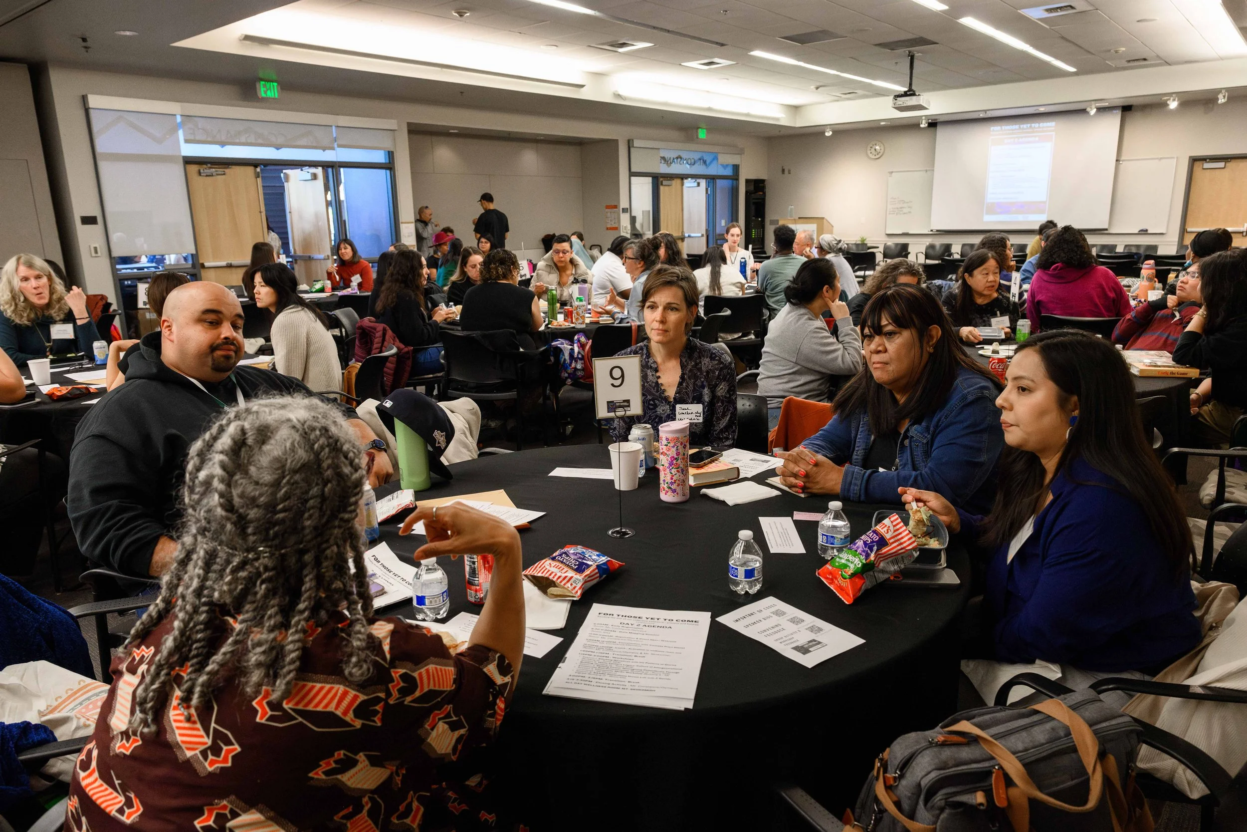 People seated at round tables in a meeting room