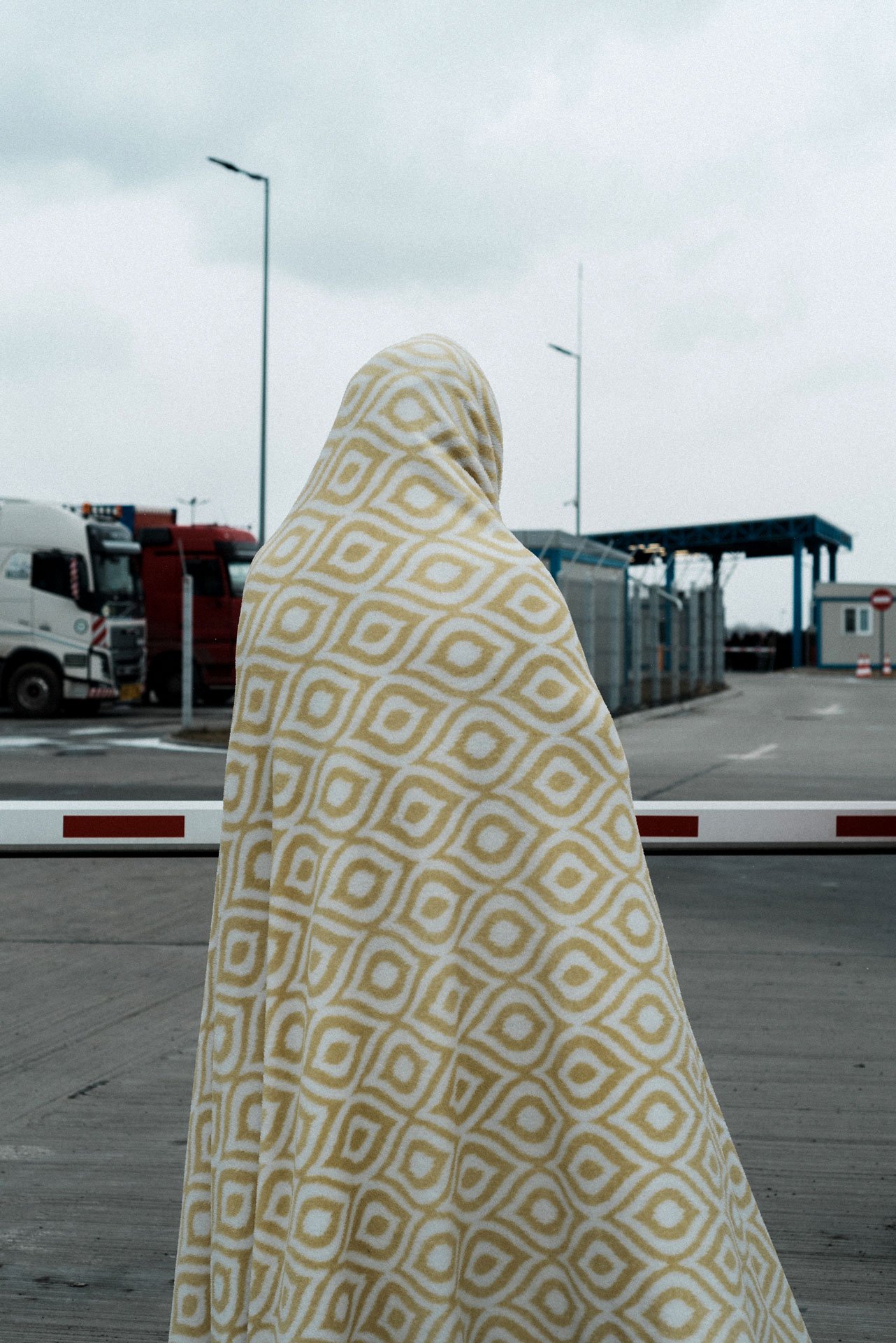A woman wrapped in a blanket waits for her family to pass the border at Isaccea, Romania.