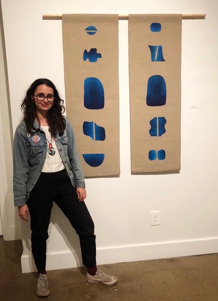 Young Puerto Rican artist Yanira Vissepo stands next to a piece in her exhibition located in Nashville, Tennessee where a percent of her profits were donated to For Such A Time As This.