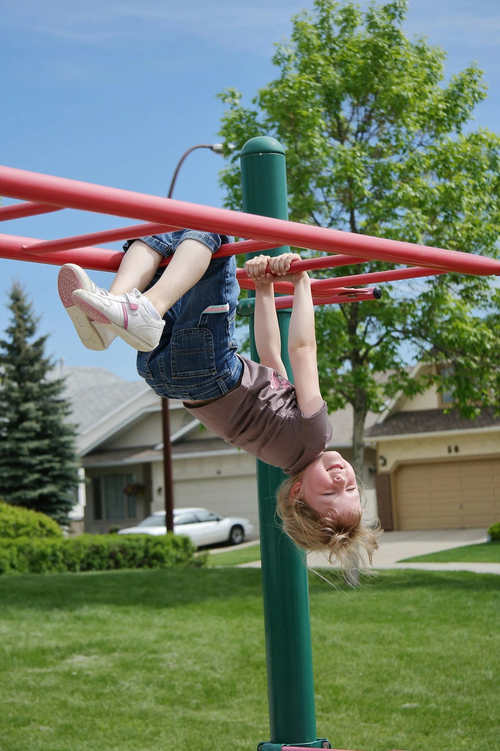 boy hanging upside down on monkey bars