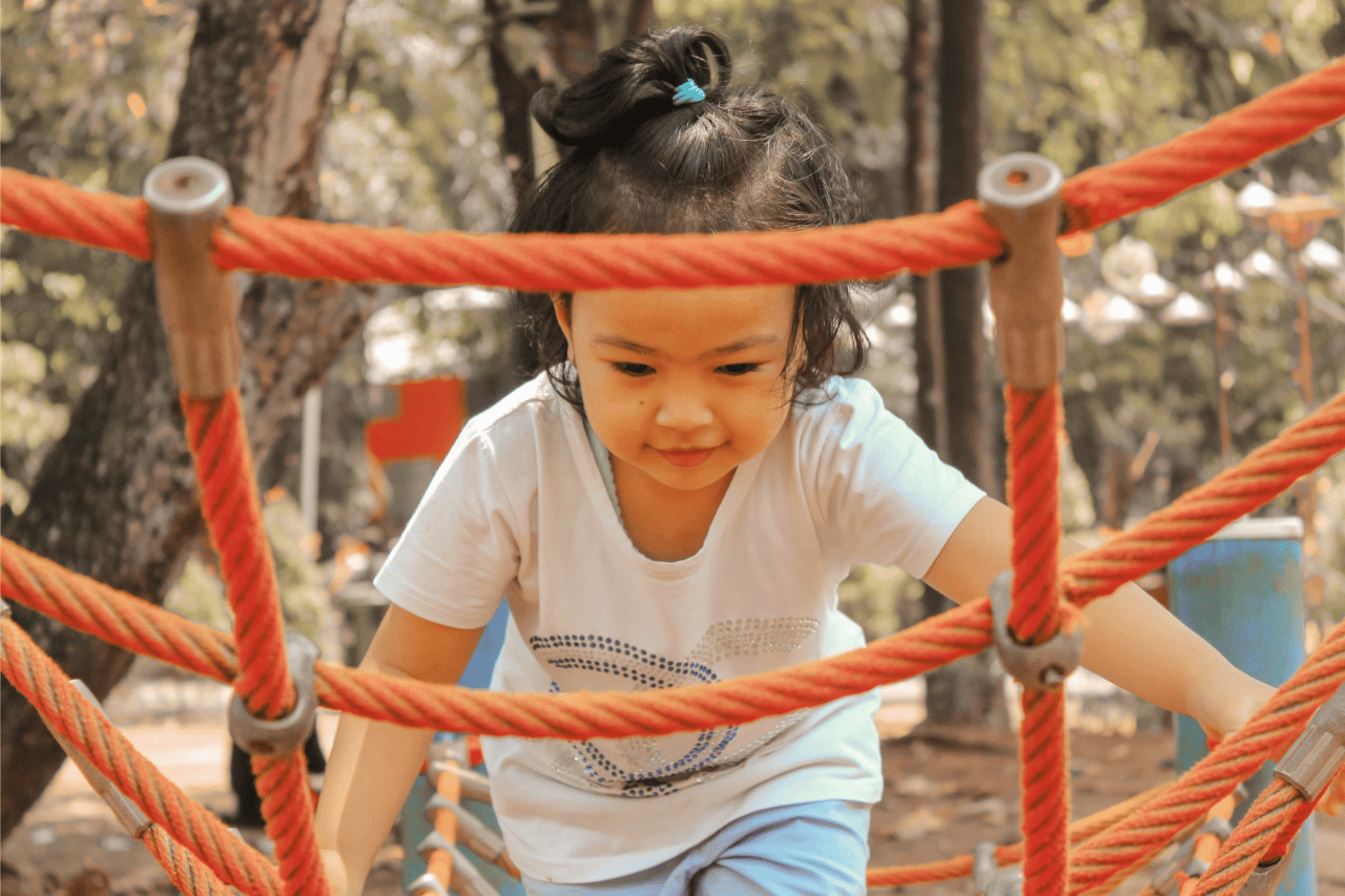 girl climbing on rope structure at park demonstrating good coordination